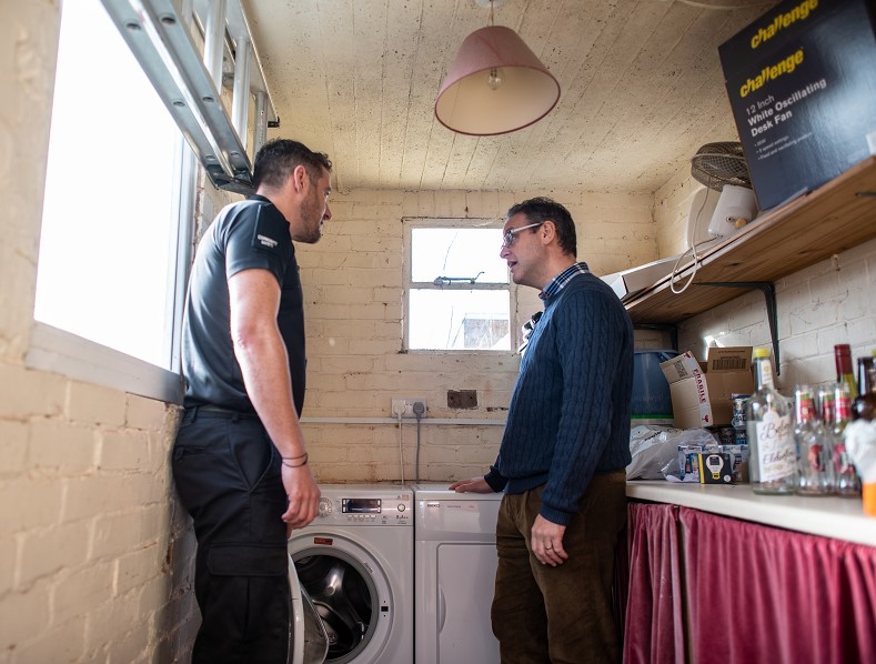 A technician standing next to a tumble dryer and washing machine
