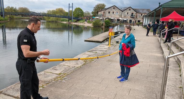 Steve Fisher from the Prevention team at Devon and Somerset Fire and Rescue Service demonstrates how to use life saving equipment to a member of the public on the quayside on Exeter Quay