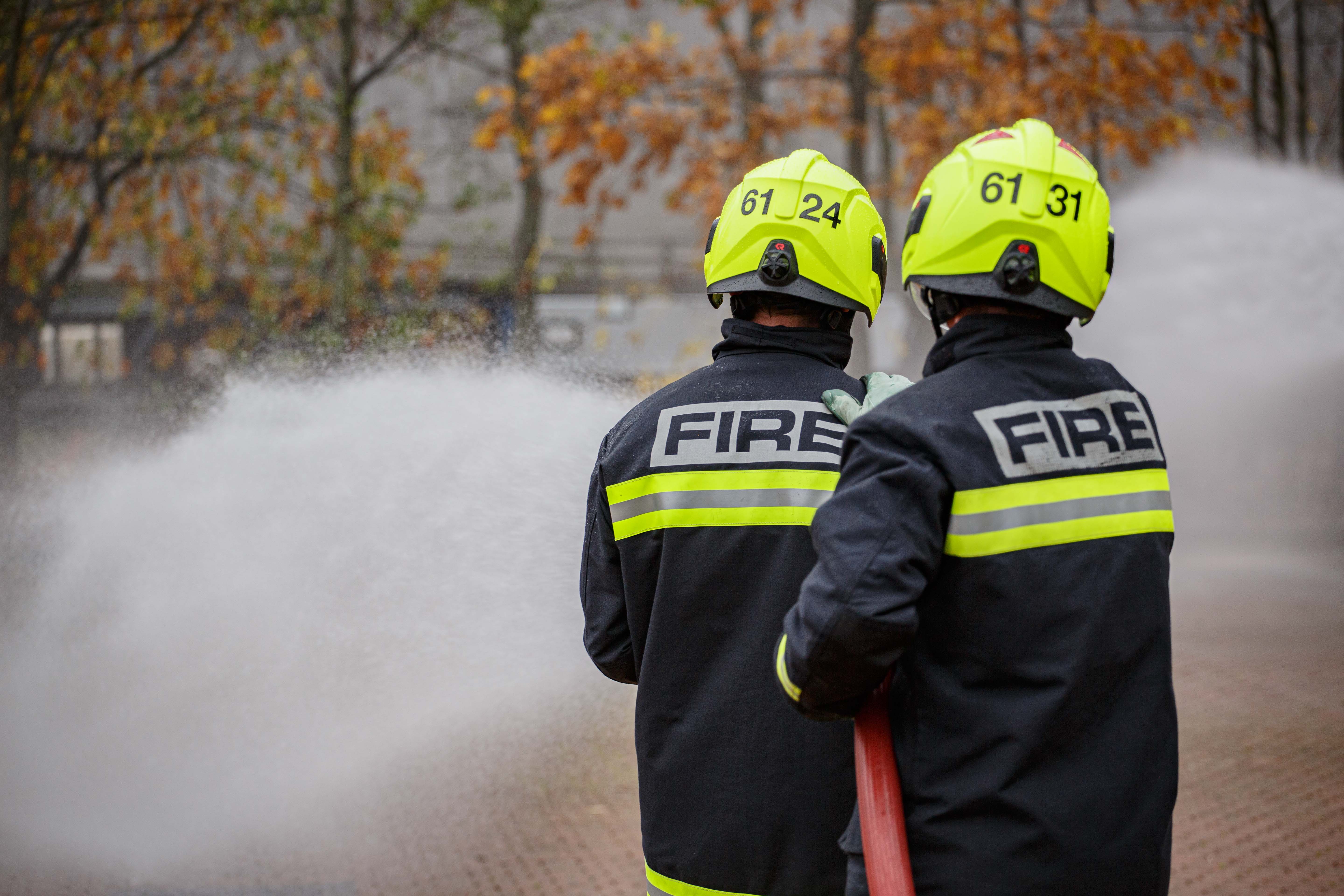 Two firefighters using a hose reel jet