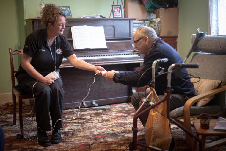 A home safety technician showing an elderly gentleman a specialised smoke alarm for people who are hard of hearing.