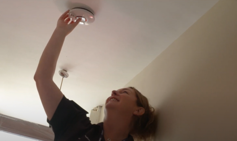 A home safety technician installing a FireAngel smoke alarm.