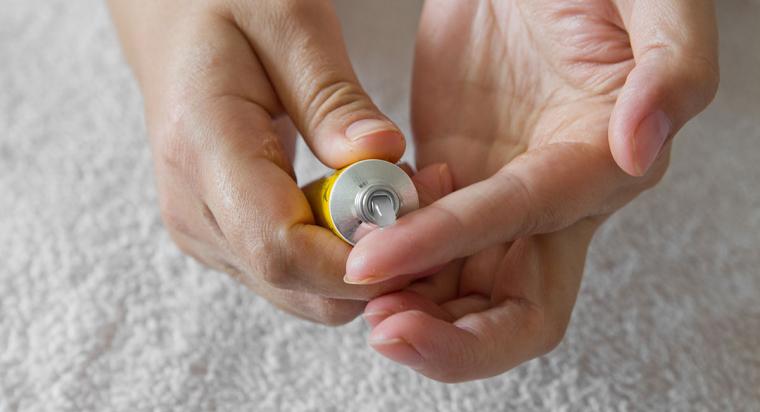 A person squeezes an emollient gel out of a yellow tube onto their hands. 