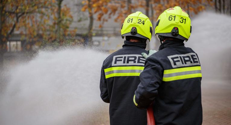 Two firefighters using a hose reel jet